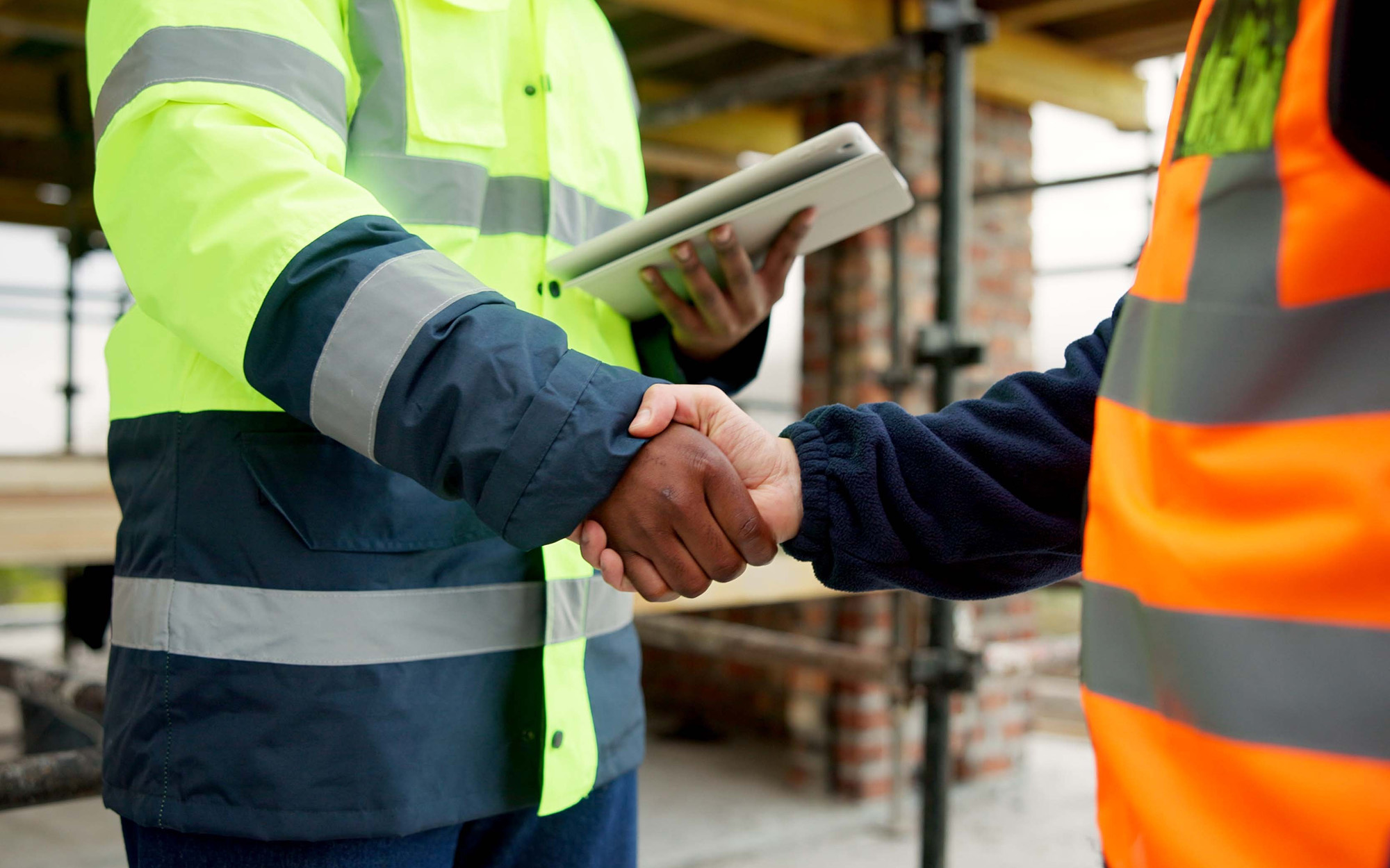 Men, shaking hands and tablet on construction site for agreement
